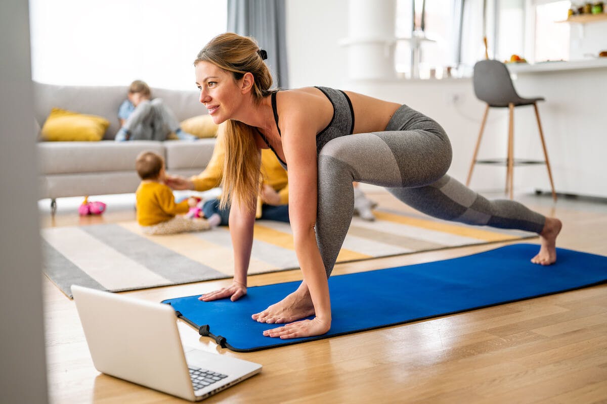 SMART fitness goals: mom practicing yoga at home while her kids play in the background