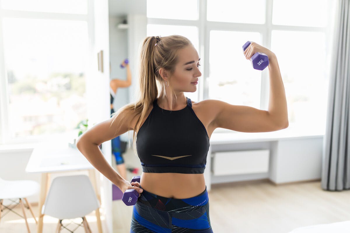 How to build muscle: woman flexing her biceps while carrying a 2KG dumbbell